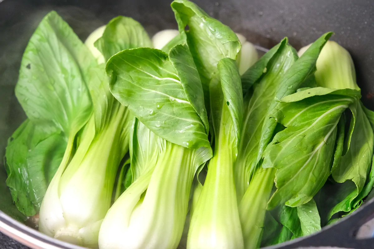 Bok choy add to the chorizo cooking with chorizo, spice and chicken broth in a pan.