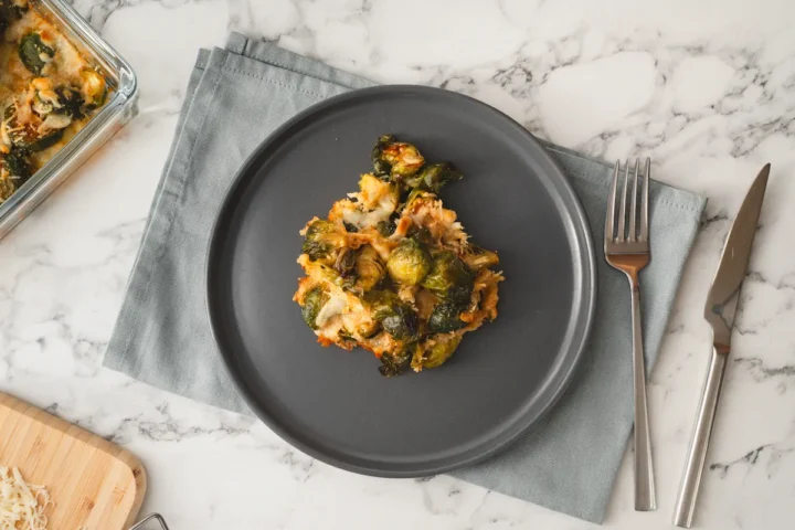 Low-carb keto Brussels sprouts casserole served on a plate with a fork and a knife.