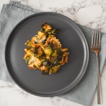 Cheesy keto Brussels sprouts casserole served on a plate with a fork.