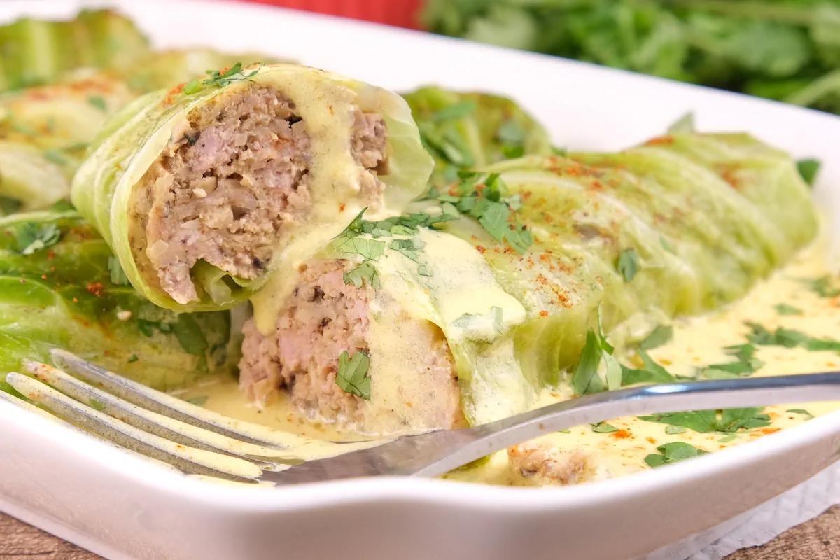 One of the keto cabbage rolls is cut to show the pork filling.