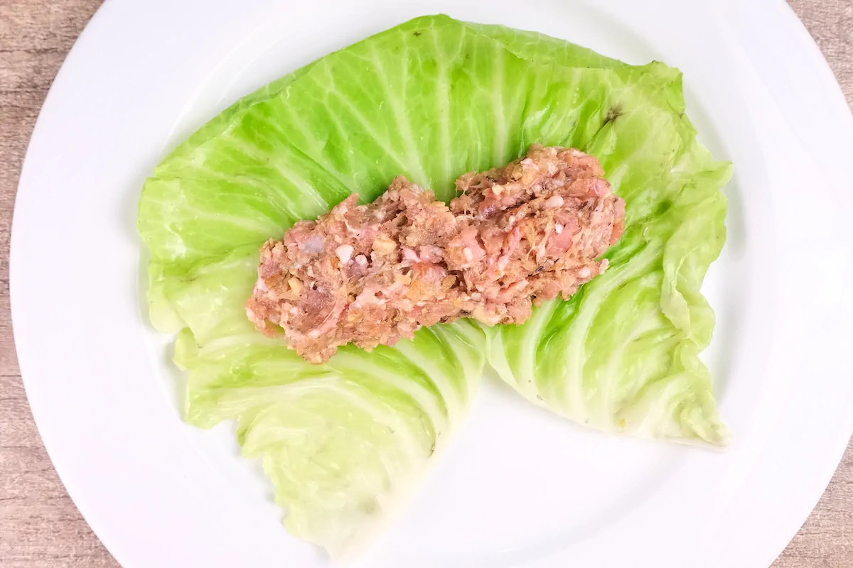 A mixture of pork and mushrooms is placed on a blanched cabbage leaf.