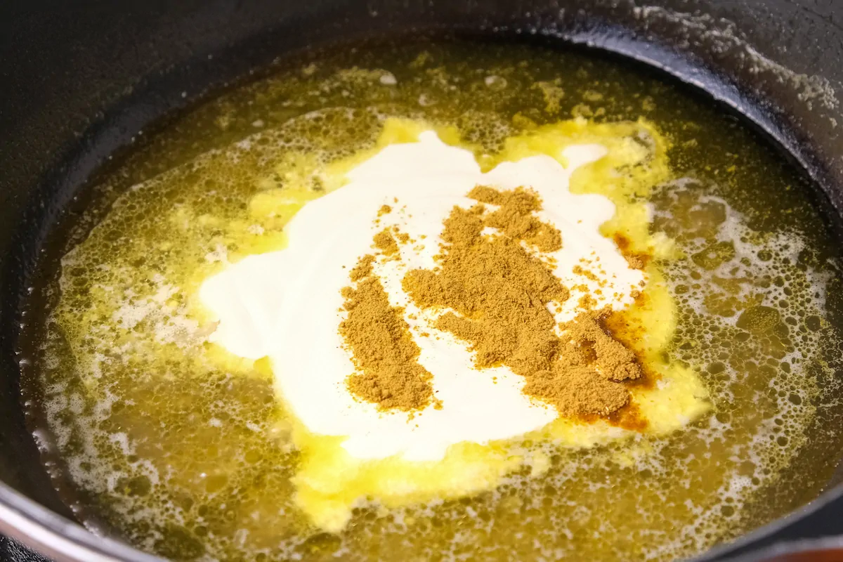 Cooking heavy cream and curry powder with the remaining stock in the pan.