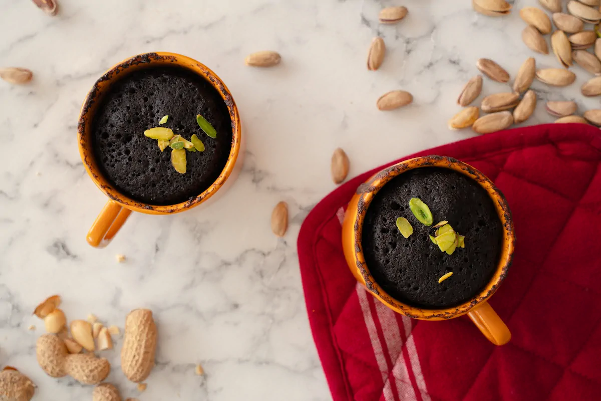 Homemade keto-friendly chocolate mug cakes garnished with nuts.