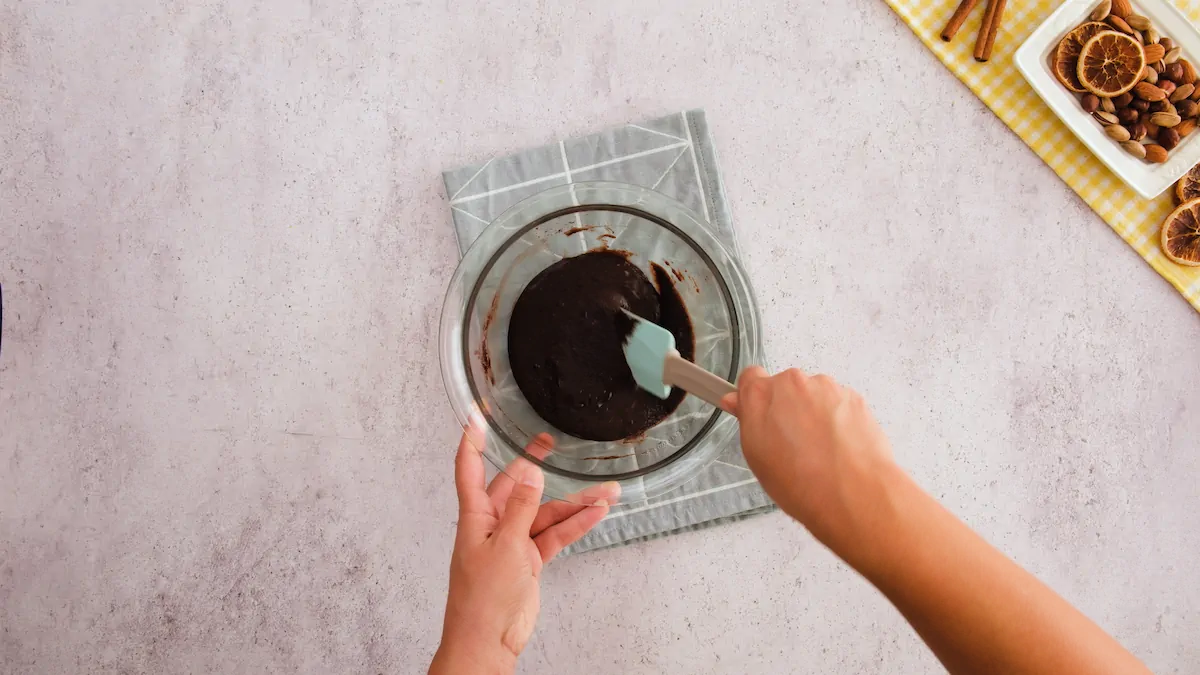 Incorporating the chopped chocolate added to the mug cake batter with a silicone spatula.
