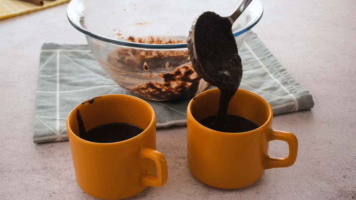 Putting chocolate cake batter into the microwave safe mugs with a ladle.