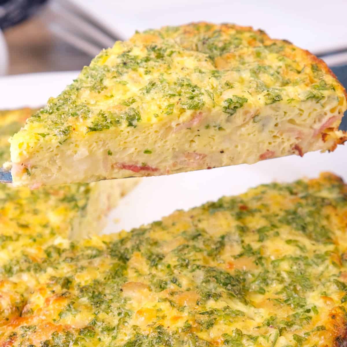 A slice taken from a circular keto crustless quiche, lifted to show its texture.