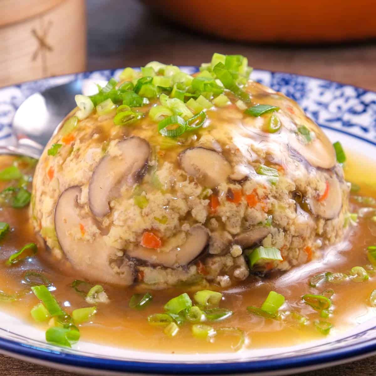 Homemade keto egg foo young served on a plate with gravy and garnished with green herbs.