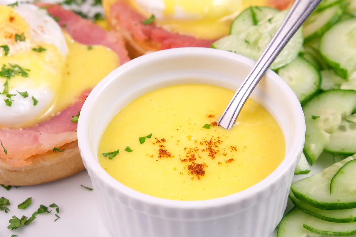A close-up picture of keto hollandaise sauce in a bowl garnished with a pinch of cayenne pepper.