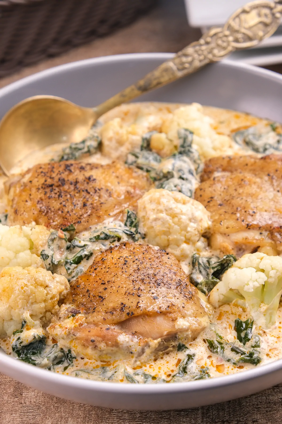 Homemade keto pesto chicken with veggies served in a bowl with a spoon.