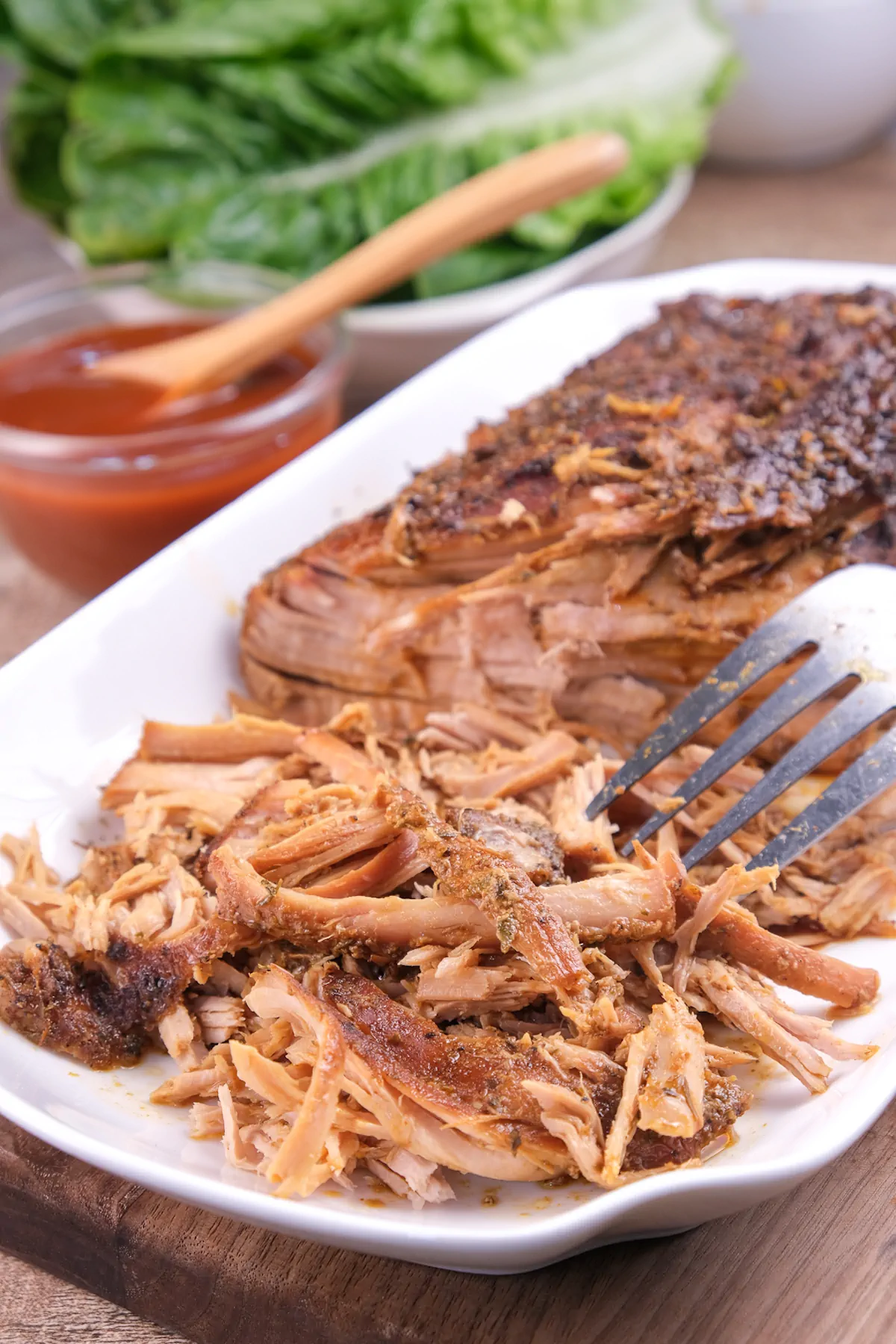 Homemade keto pork cooked in slow cooker getting shredded with a fork.