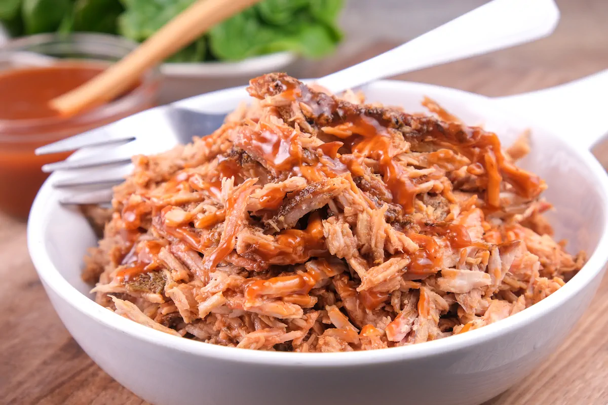 Bowl of homemade keto pulled pork in slow cooker and ready to eat with a fork.