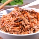 Homemade keto pulled pork cooked in slow cooker served in a bowl with a fork.