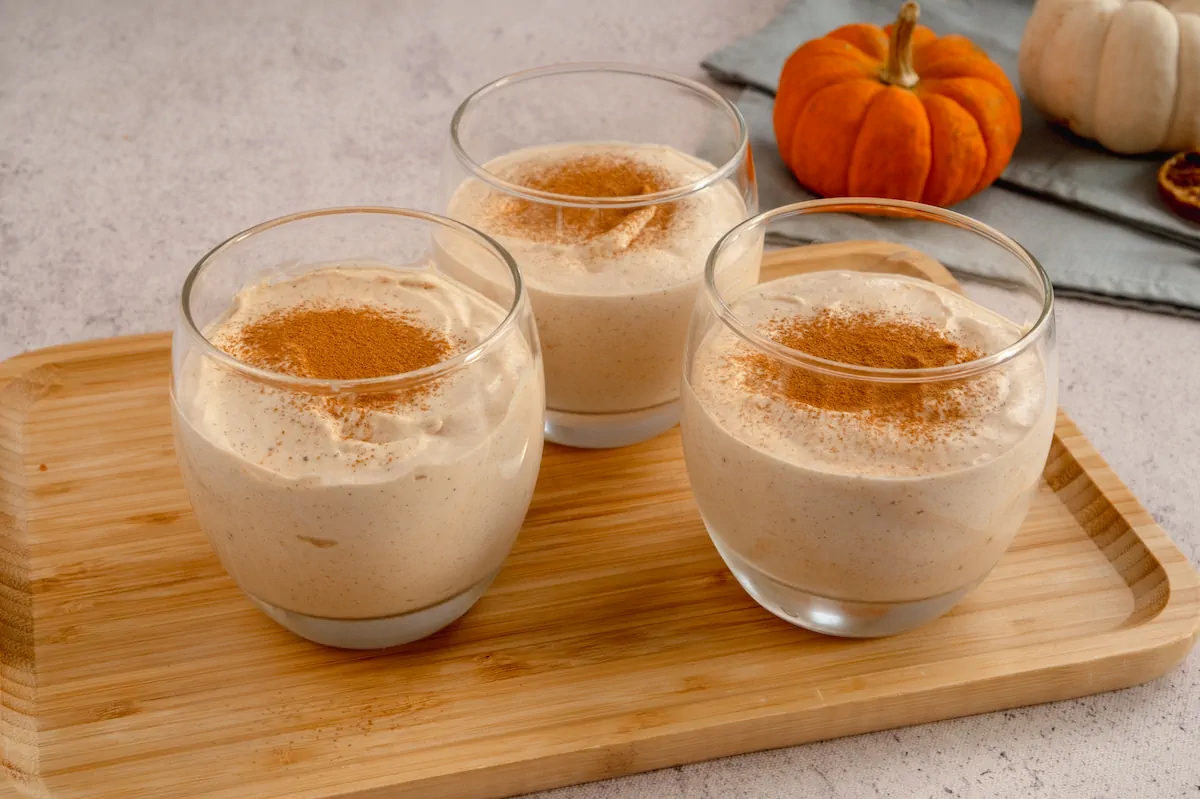 Homemade keto pumpkin cheesecake mousse recipe served in three transparent glasses and sprinkled with cinnamon powder.
