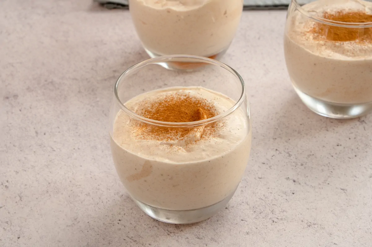 Low-carb keto pumpkin cheesecake mousse recipe served in three transparent glasses and sprinkled with cinnamon powder.