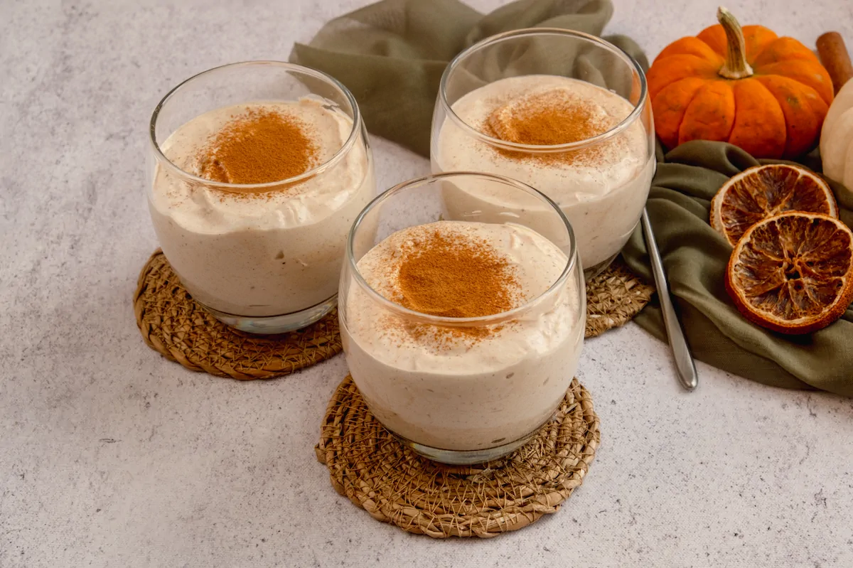 Homemade keto pumpkin cheesecake mousse in three transparent glasses and sprinkled with cinnamon powder.