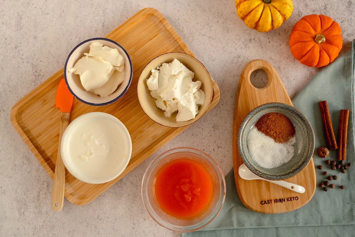 All the ingredients required to make keto pumpkin cheesecake gathered and displayed on the table.