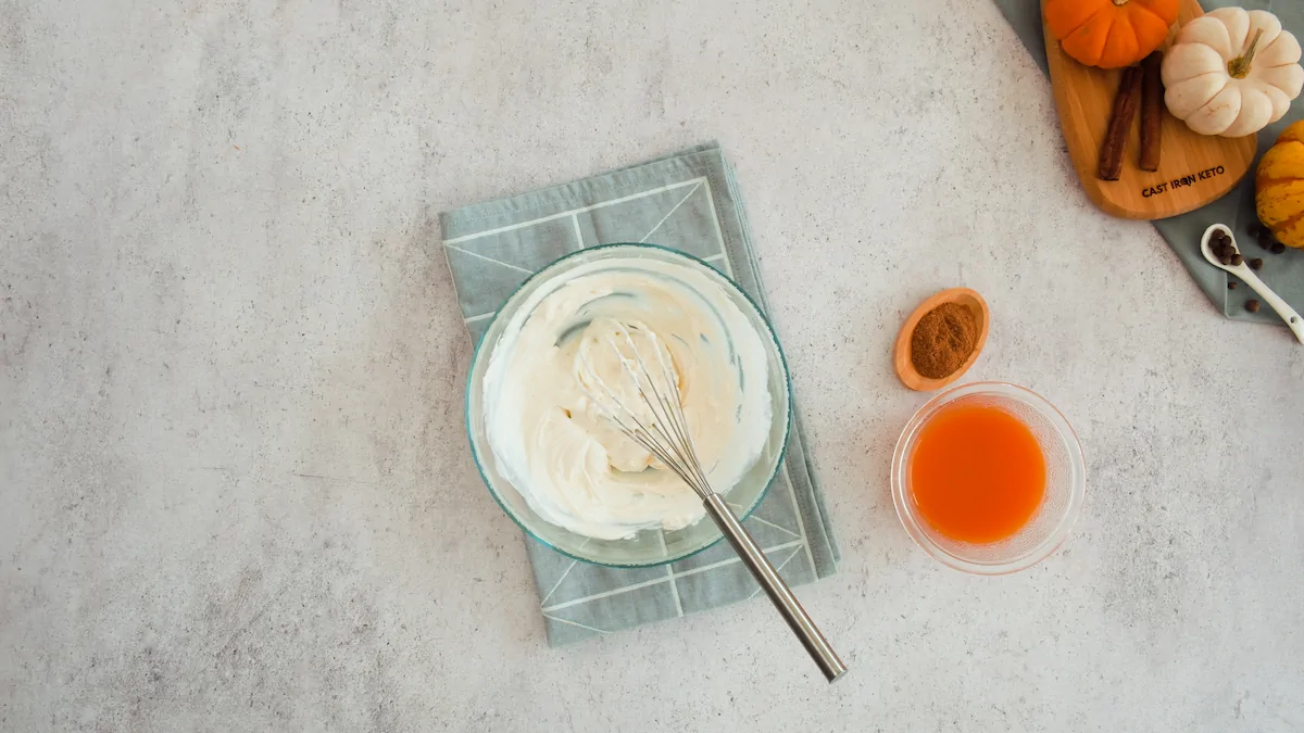 Whisked cream cheese and labneh in a bowl alongside a bowl of pumpkin puree.