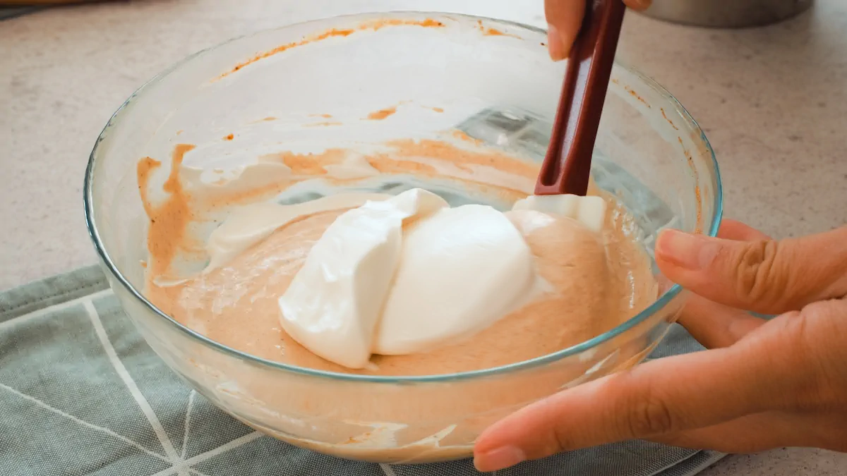 Folding the whipped cream into the pumpkin mixture with a spatula.