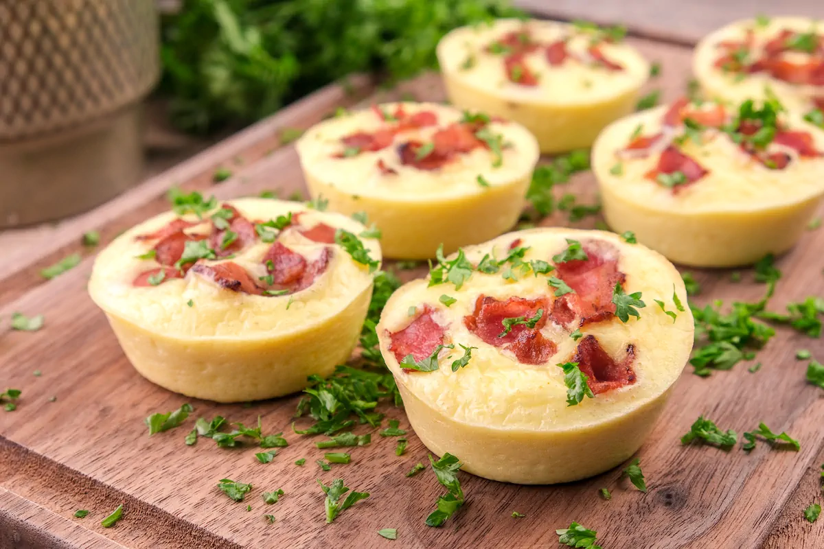 Keto Starbucks egg bites presented on a wooden tray and garnished with fresh herbs.