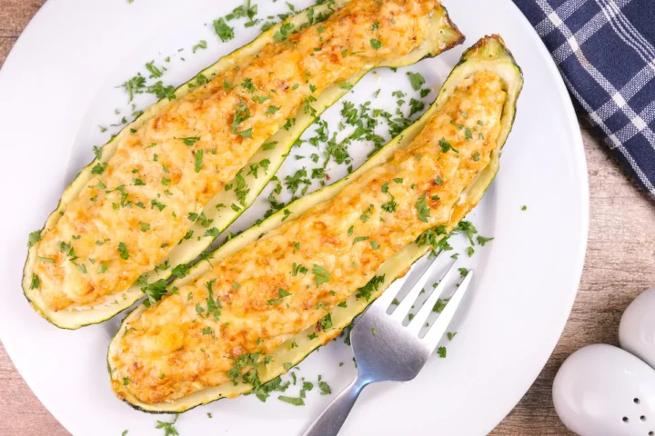 A plate of keto-friendly stuffed zucchini boats topped with a herb garnish.