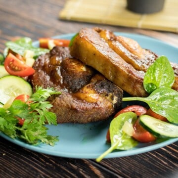 Oven baked beef ribs with mixed vegetable salad on a blue plate.