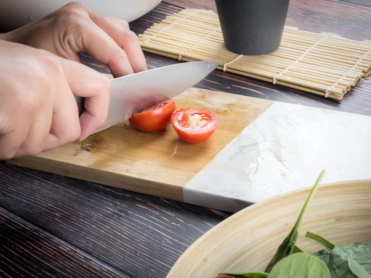 Cutting tomatoes with a knife on a chopping board.