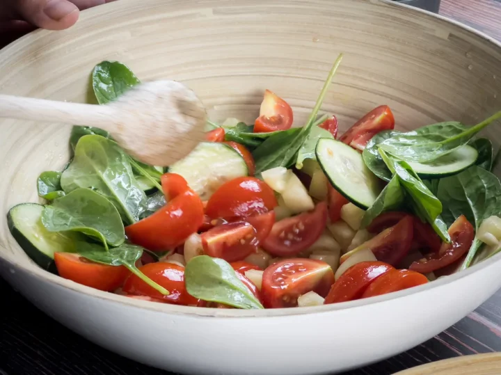 Mixing the vegetable salad in a bowl with a wooden spoon.
