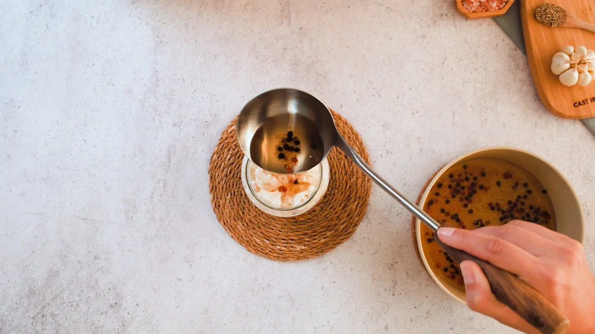 Adding the brine into a glass jar with cauliflower florets with a ladle.