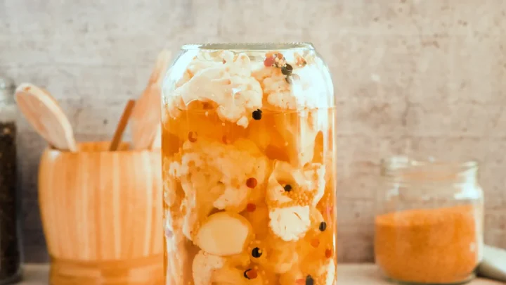 A glass jar with cauliflower and brine placed upside down on the kitchen counter.