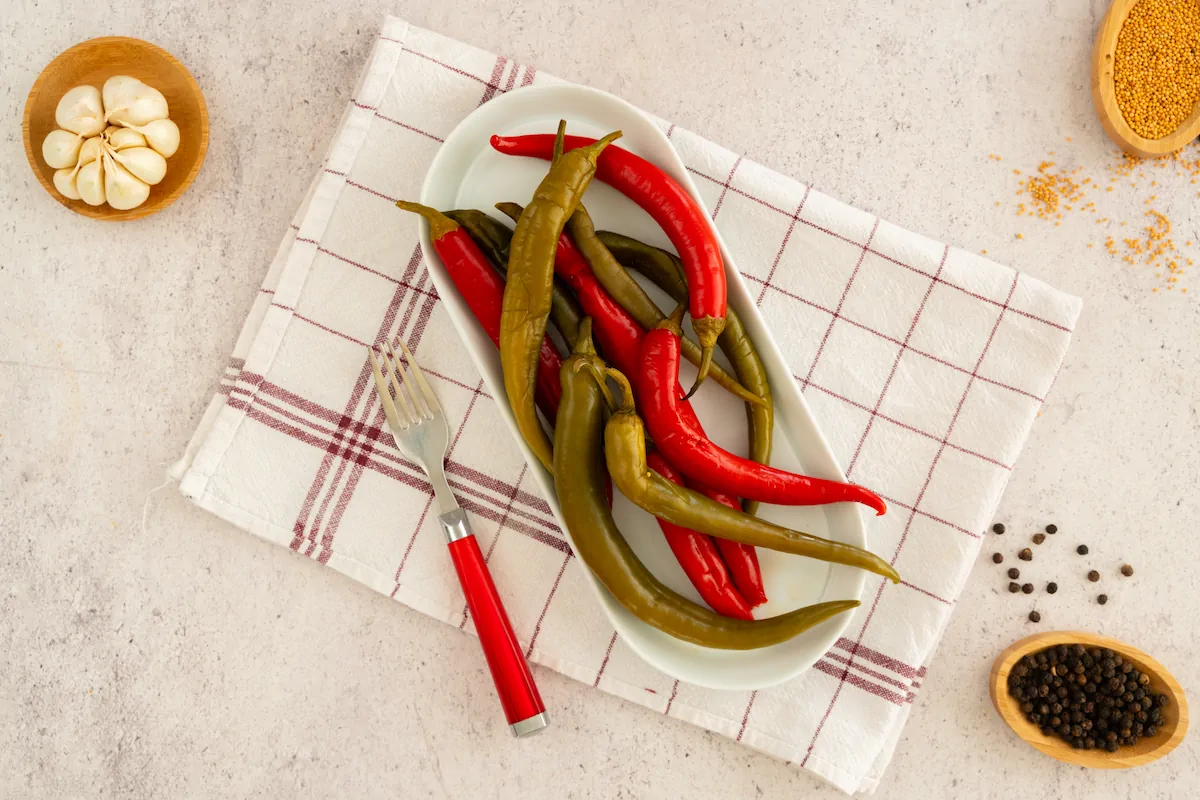 Low-carb pickled peppers served on a white plate next to a fork.