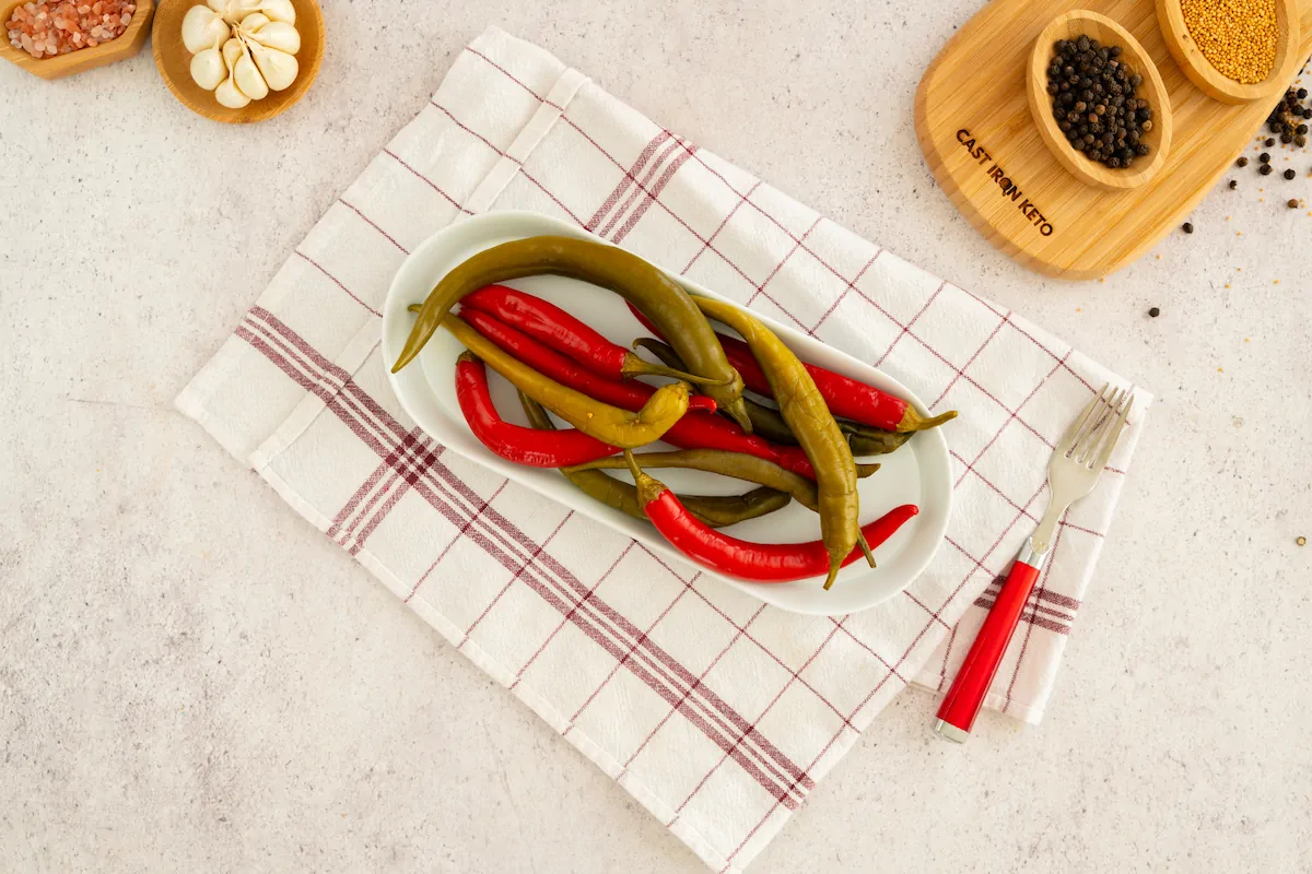 Pickled peppers served on a plate alongside a fork.
