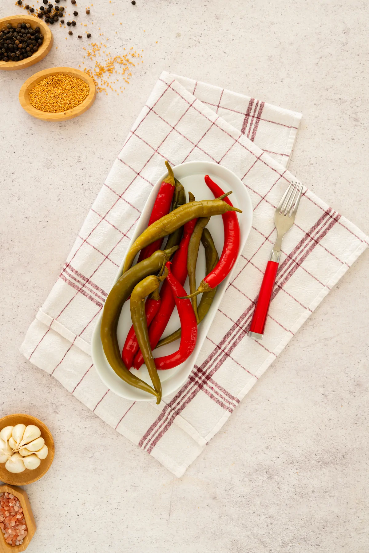 Homemade pickled peppers on a plate, accompanied by a fork.