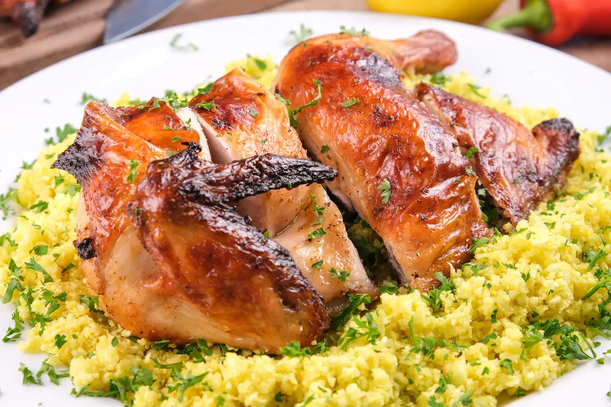 Homemade pollo asado served on a bed of cauliflower rice and garnished with fresh herbs.
