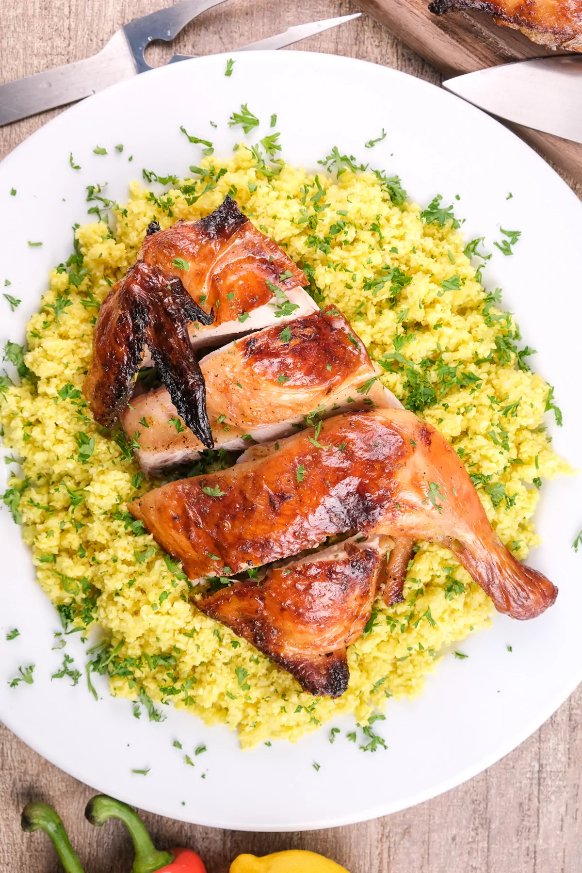 Pollo asado over cauliflower rice, garnished with fresh herbs, served on a plate.