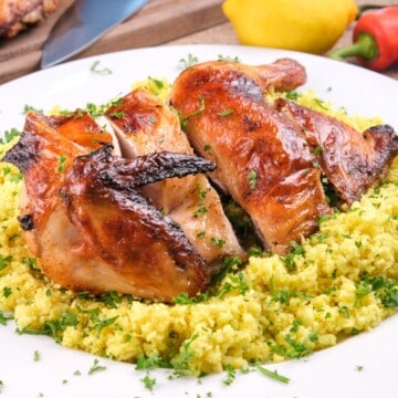 Keto pollo asado plated on cauliflower rice, garnished with fresh herbs.