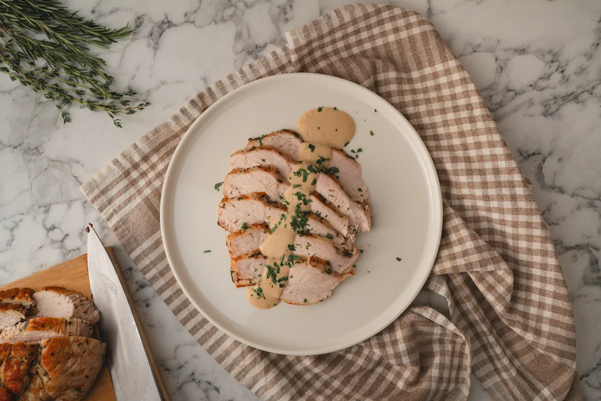 Sliced roasted turkey with keto gravy poured on it and served on a plate.