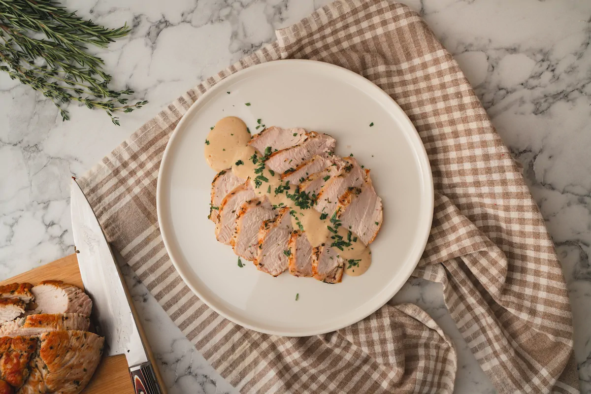Roasted turkey breast slices with keto gravy, presented on a plate.