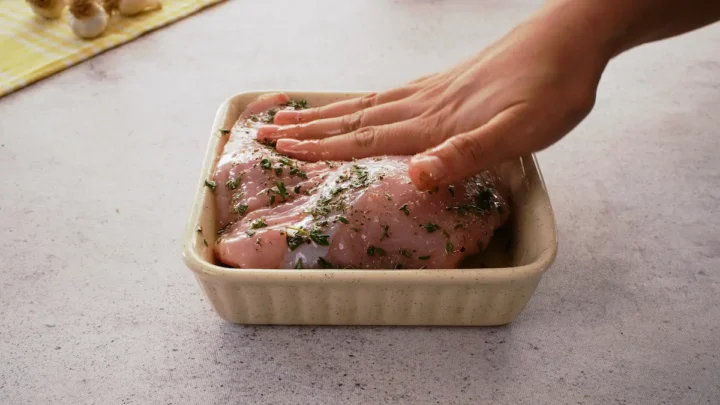 Rubbing the turkey breast with dried herbs, olive oil, and seasoning in a bowl.