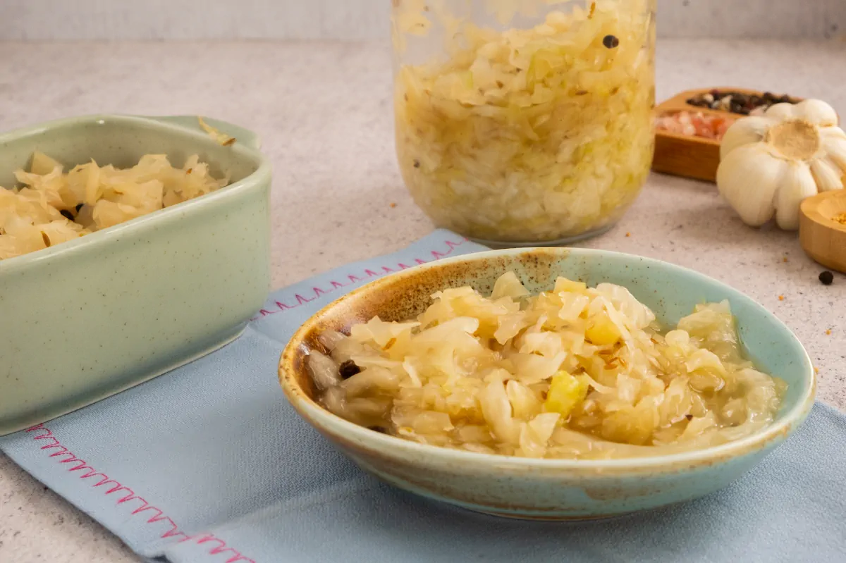 Tangy and crunchy sauerkraut served in a ceramic bowl from a glass jar.