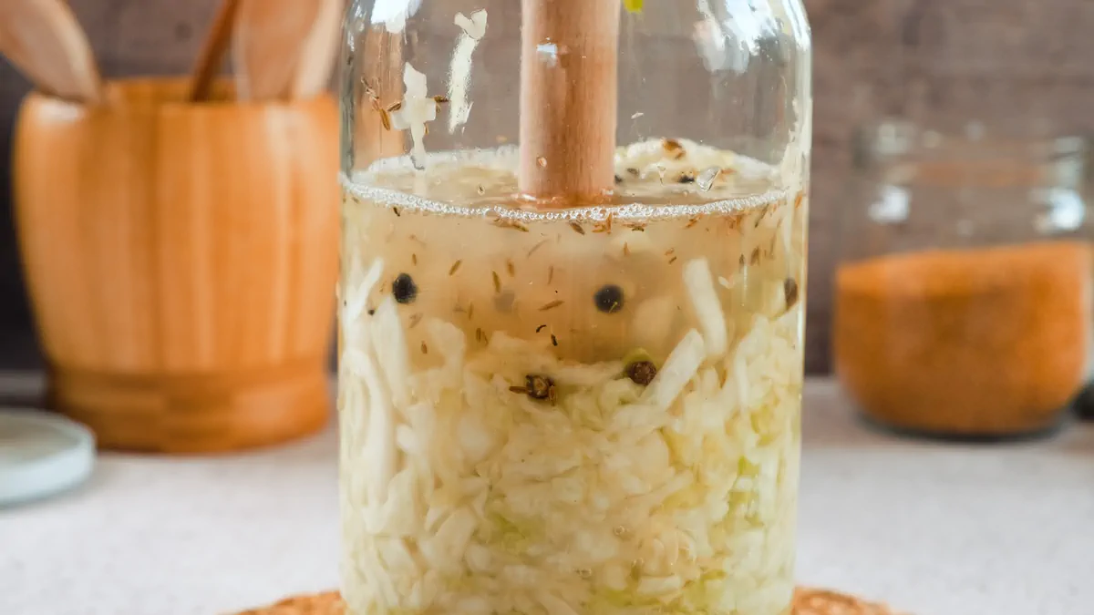 Pressing down the cabbage in a glass jar with a muddler.