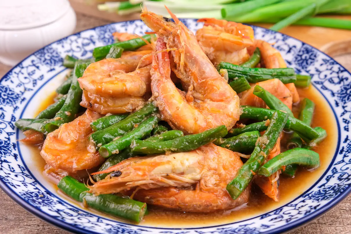 Shrimp stir fry with string beans served on a plate.