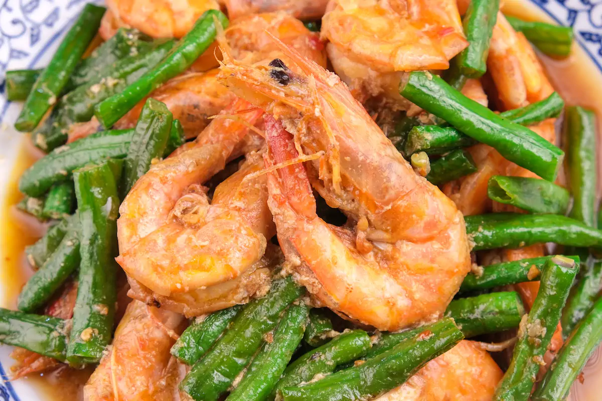 Close up shot of shrimp stir fry with string beans served on a plate.
