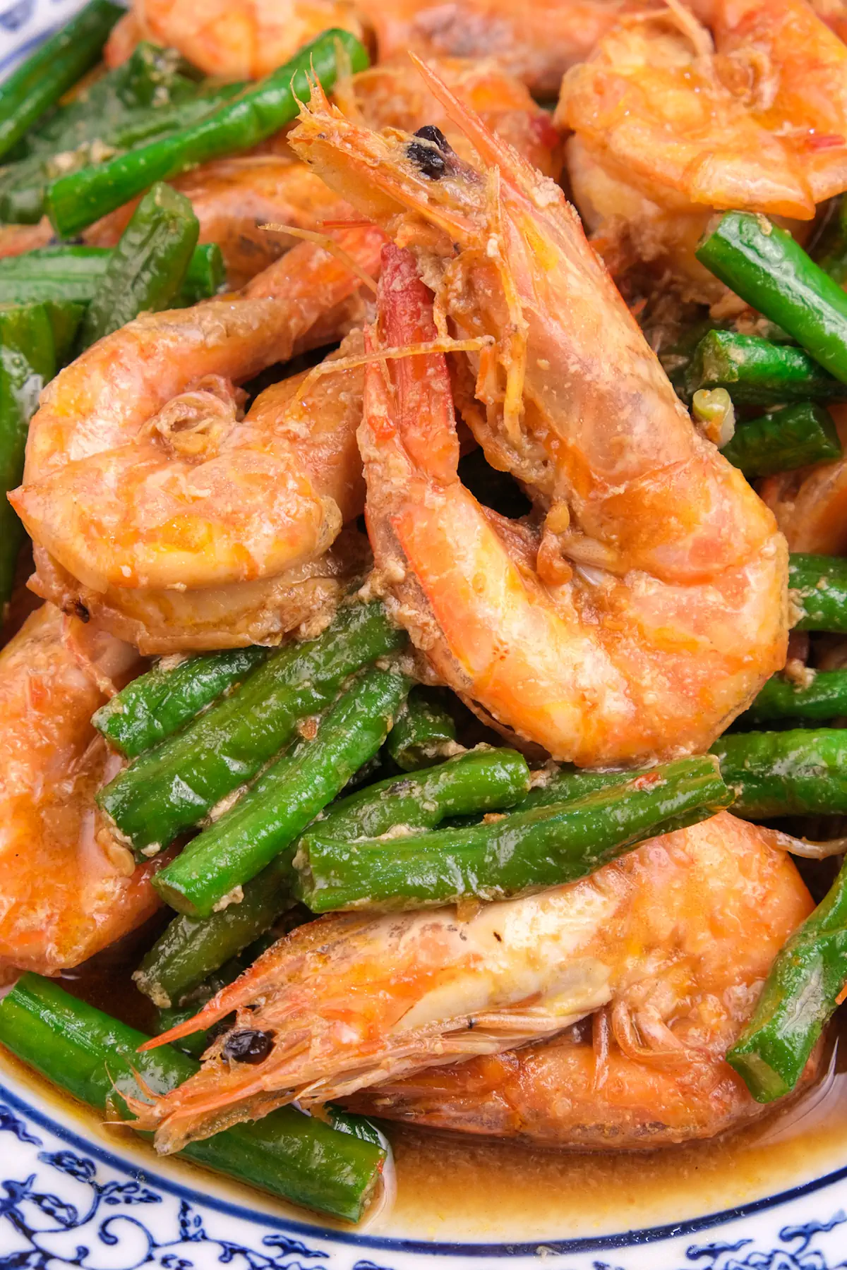 Low-carb shrimp stir fry with string beans in spicy sambal oelek served on a plate.