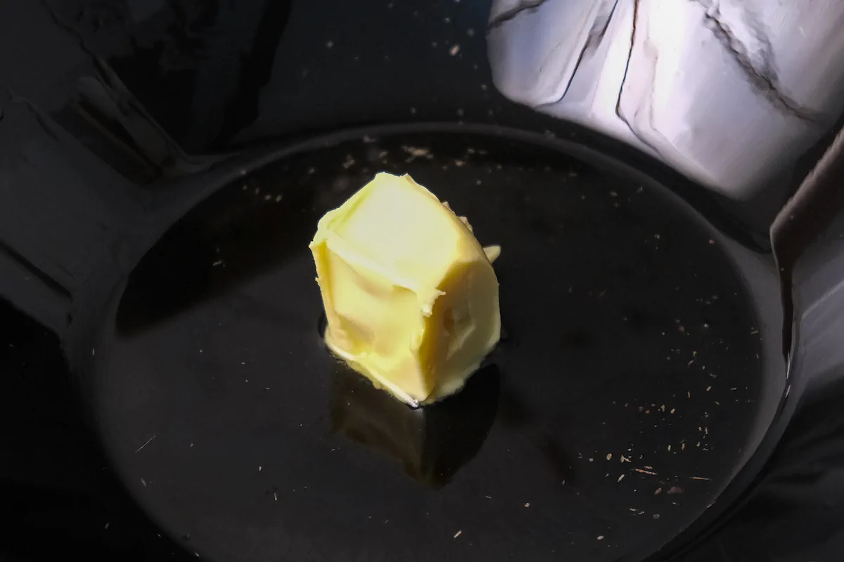 A cube of putter getting melted in a wok.