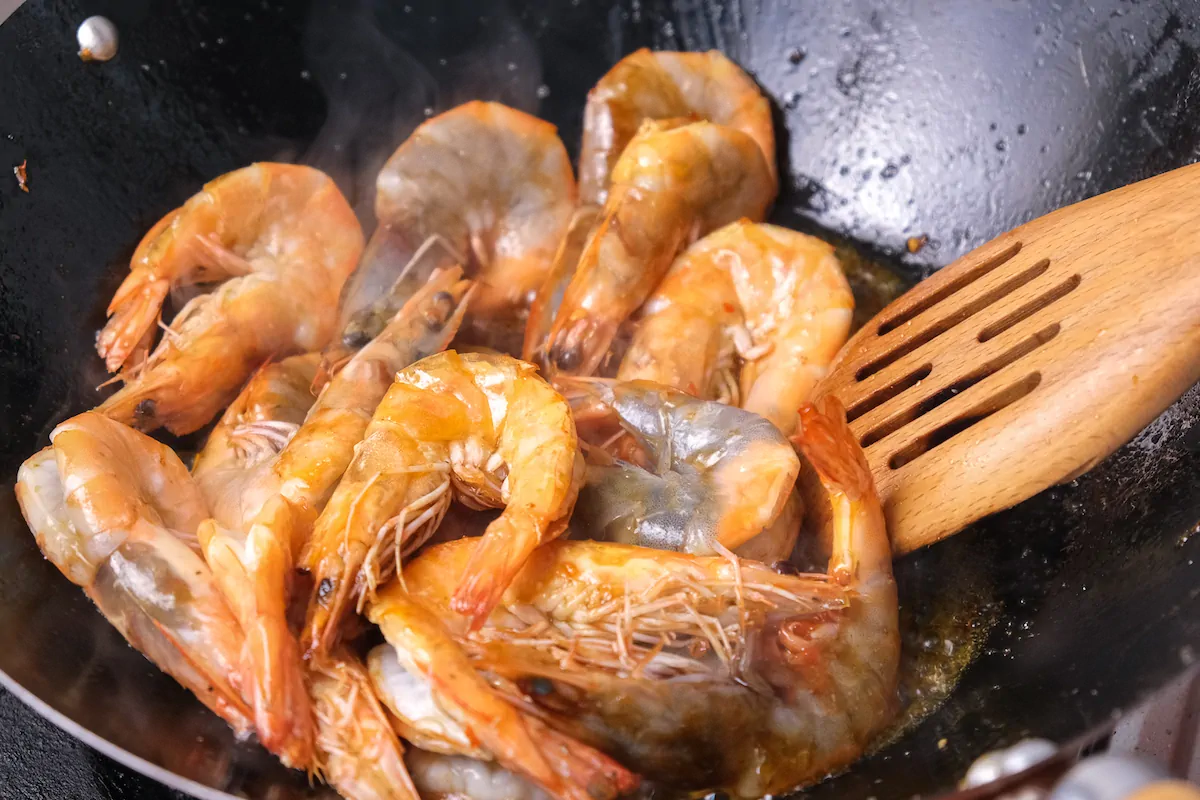 Shrimps being stir fried in a wok.