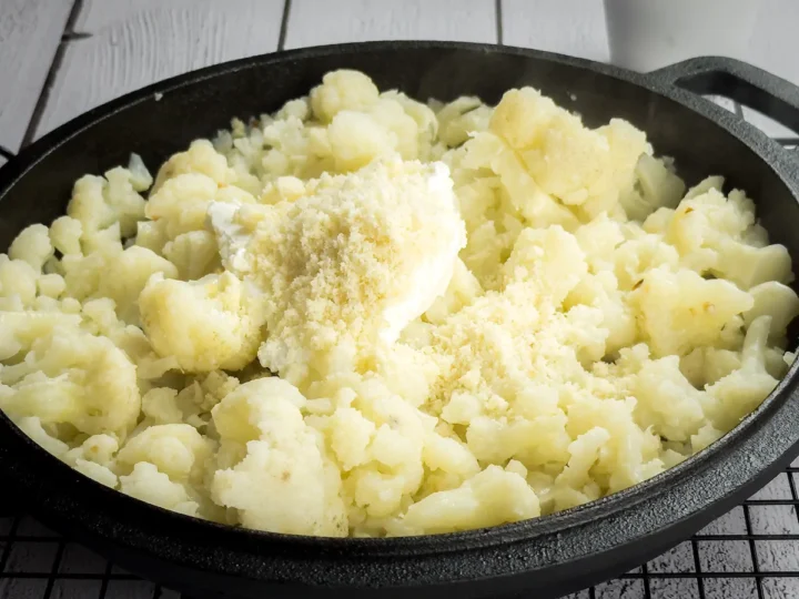 Cooking steamed cauliflower florets with cream cheese and grated Parmesan cheese.