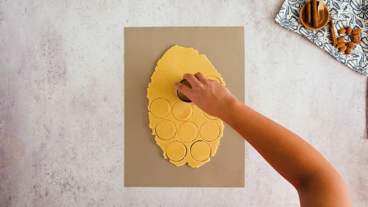 Cutting the rolled cookie dough with a cookie cutter.