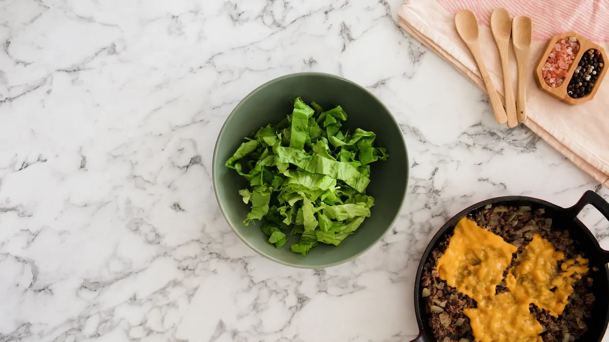 A bowl with large pieces of lettuce leaves alongside a skillet with cooked cheesy ground beef.