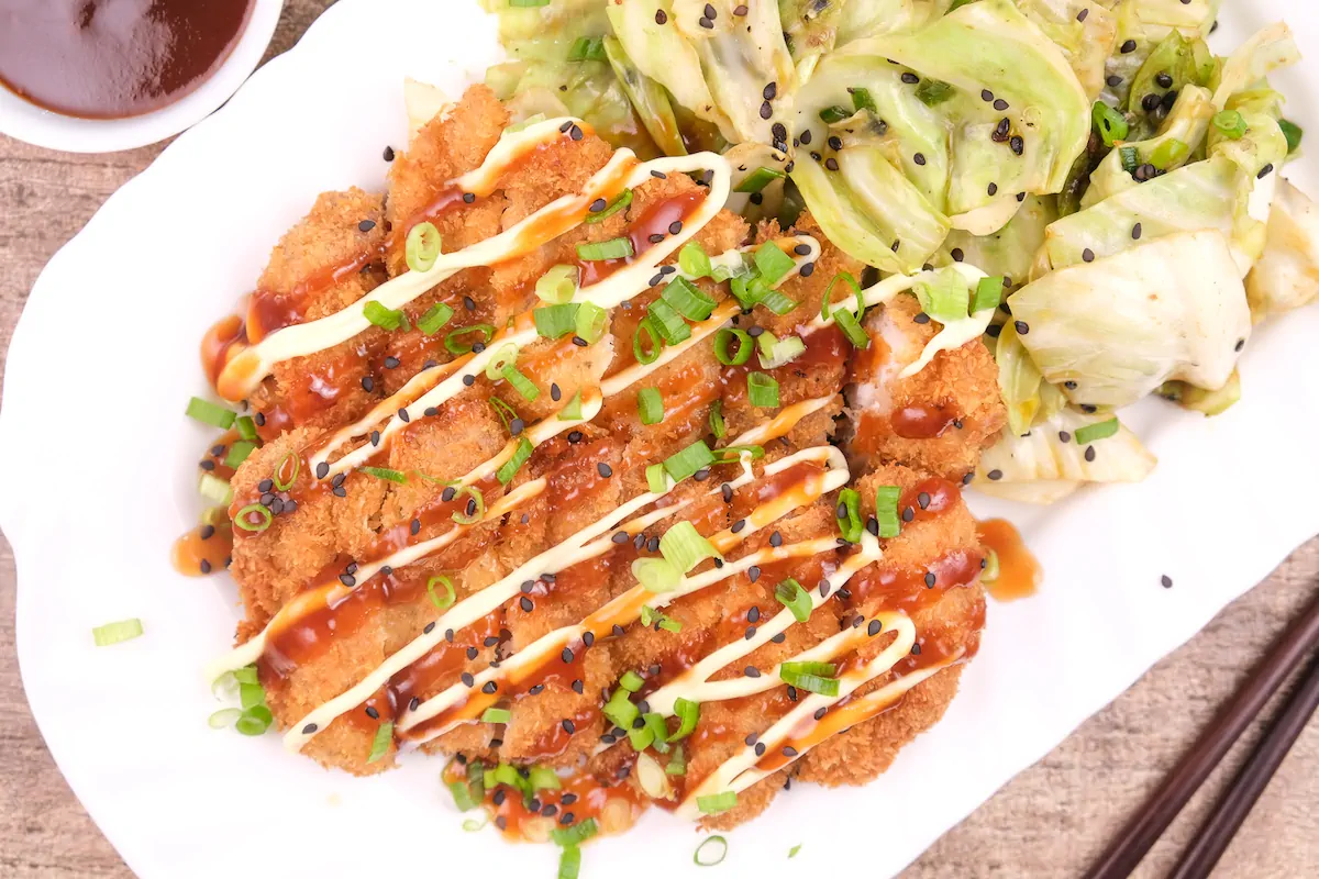 Chicken katsu with Japanese mayo and katsu sauce served with a side of cabbage.