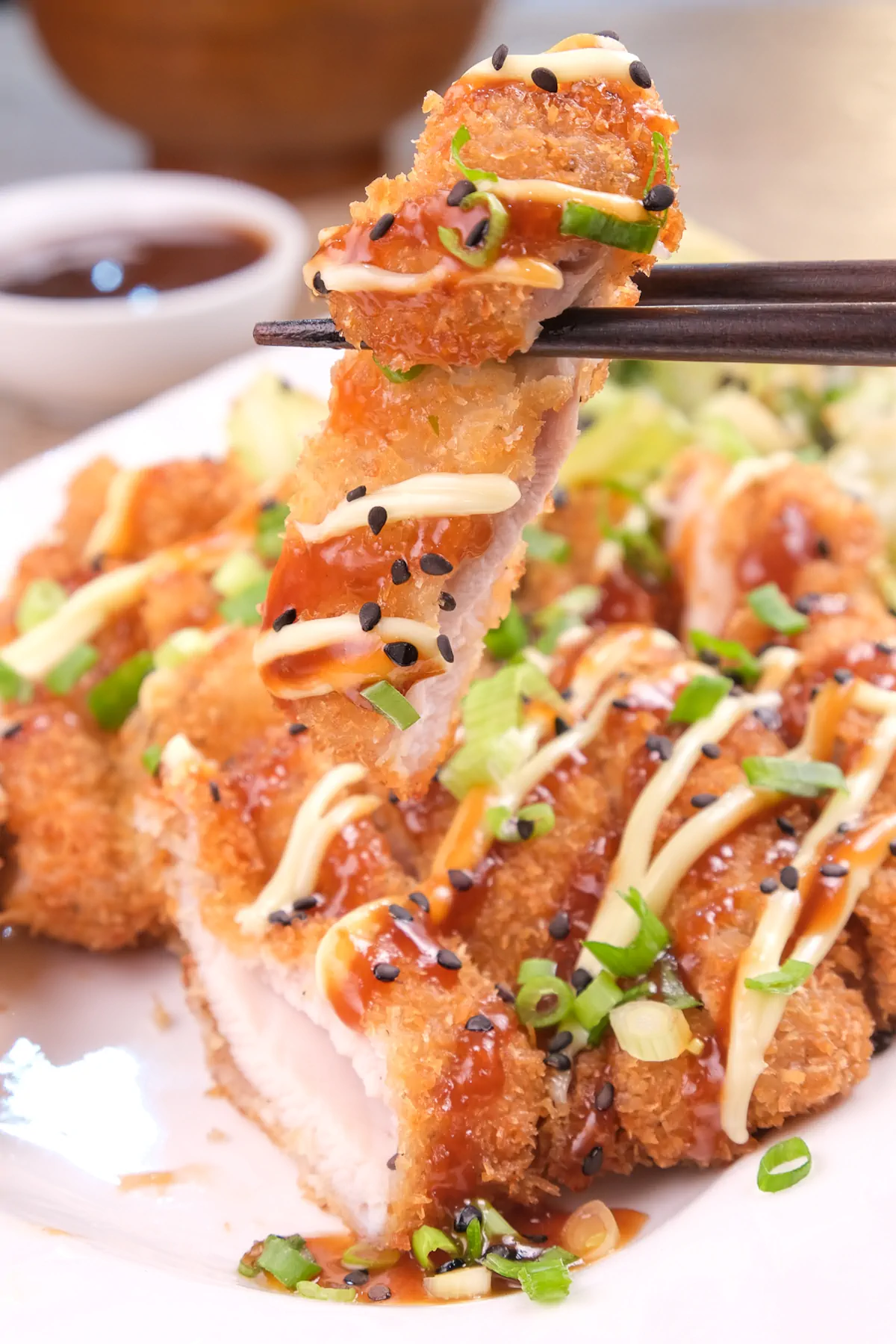 Picking up a piece of chicken katsu using chopsticks.